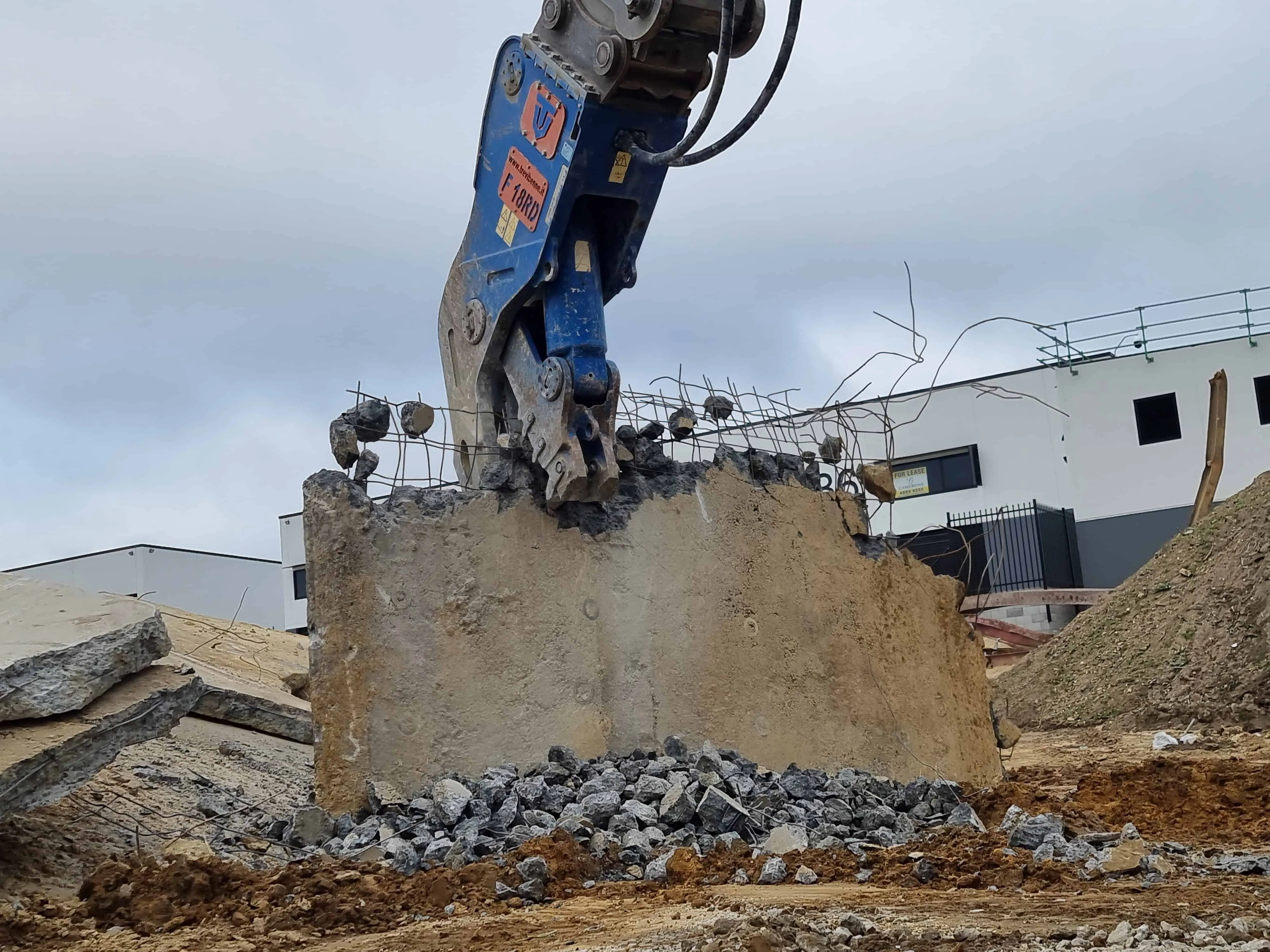 Excavator with a pulverizer attachment sizing broken concrete