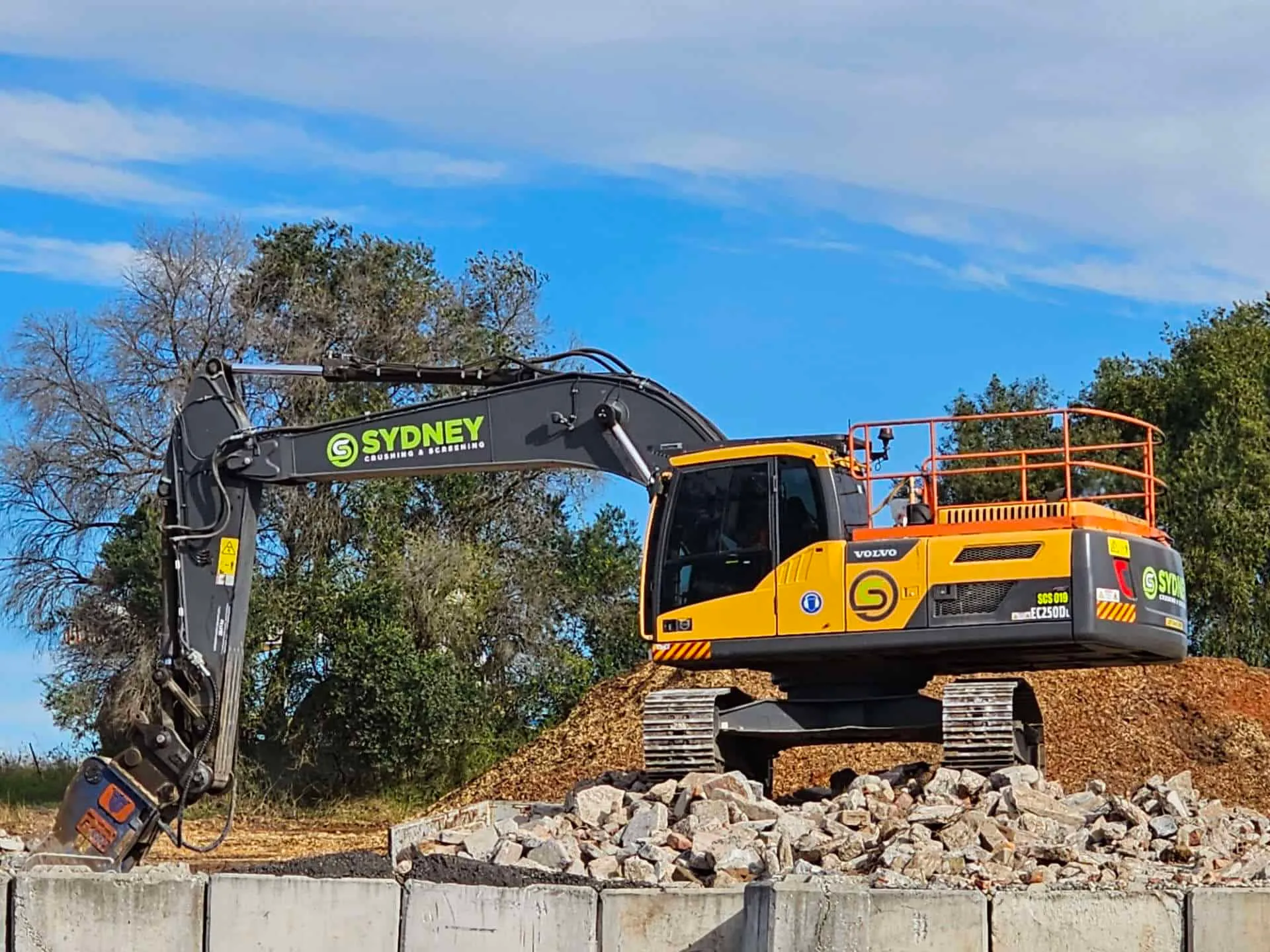Excavator working a stockpile under a clear sky