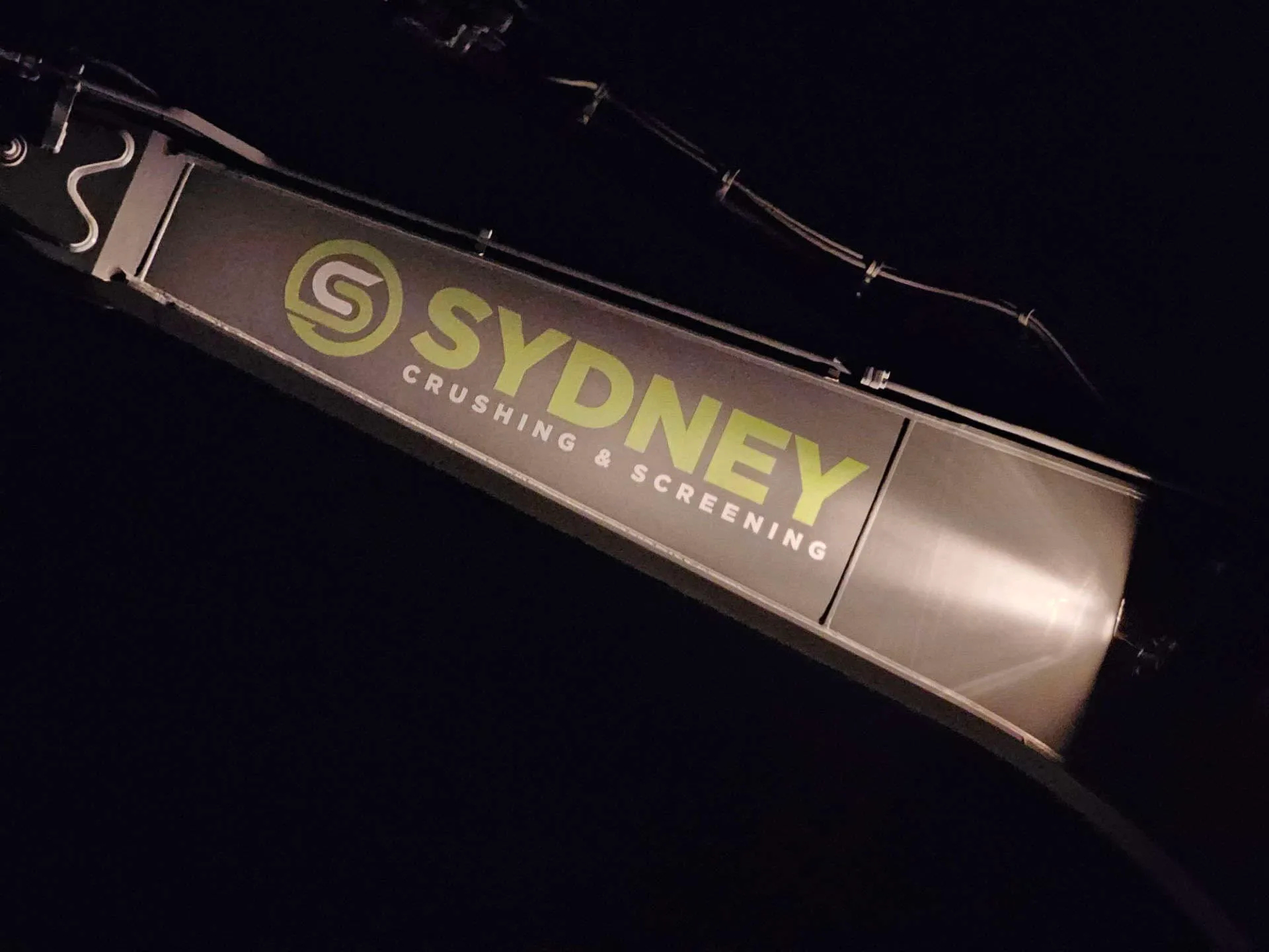 Sydney Crushing & Screening branding lit up on a conveyor at night