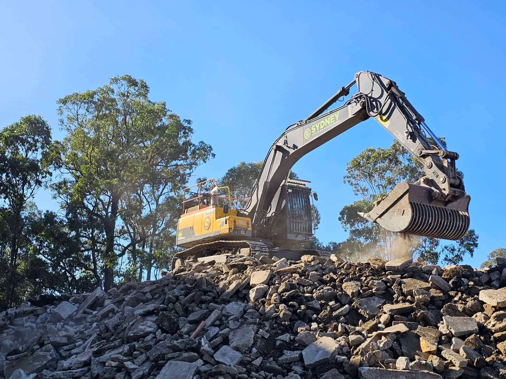 Excavator feeding broken concrete into the crusher