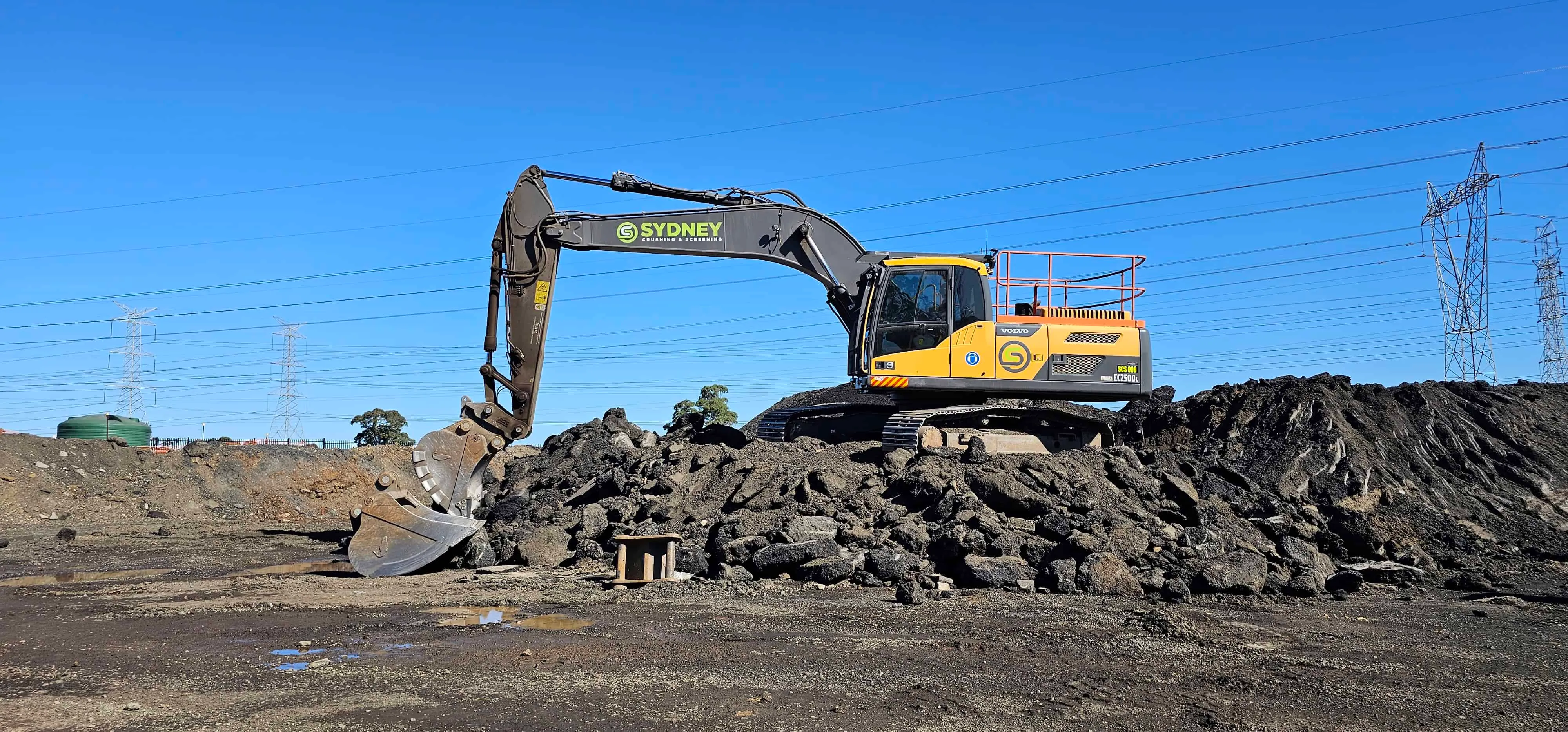 Excavator sorting a pile of broken asphalt before crushing