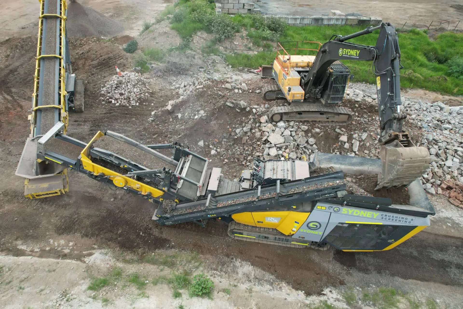 Aerial view of a crusher and conveyor processing concrete on site