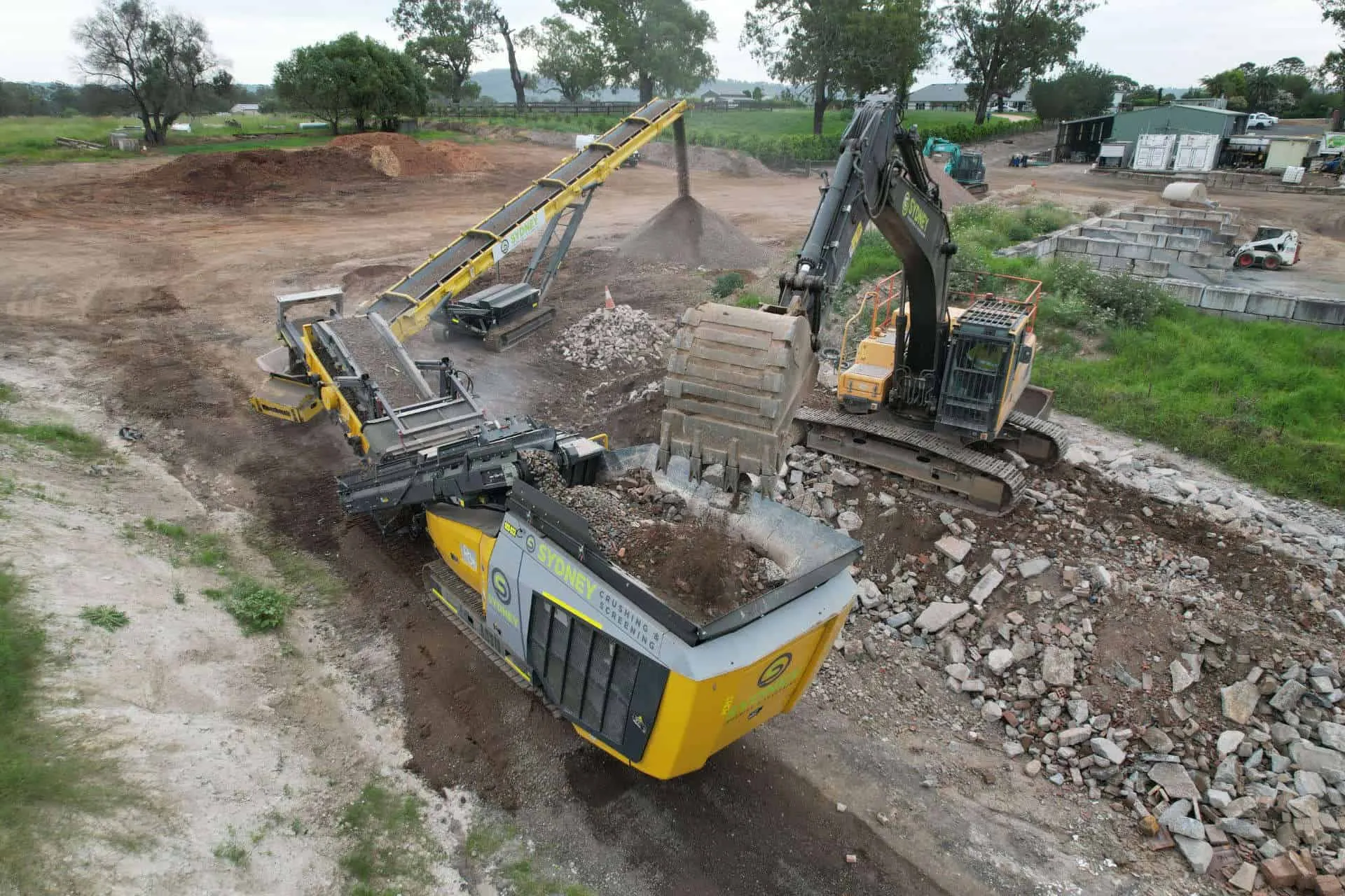 Crushed concrete being loaded into a truck beside the crusher